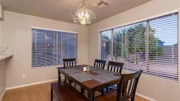 A dining area with a wooden table, four chairs, and a chandelier.