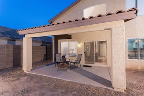 A covered patio with a fire pit, outdoor seating, and sliding glass doors leading to a room. - Arrowhead Area, Quiet, Comfy, 4 TVs (Peoria)
