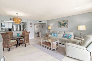 A living room with a sofa, coffee table, and dining area with chairs.