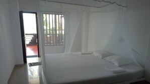 A bedroom with a bed, a window with bars, and a view of the outside. - Githmini Beach Guest House & Toures (Hikkaduwa)
