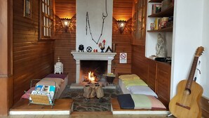 A cozy room with a fireplace, wooden walls, and a bookshelf. - Casa da Vila (Penamacor)