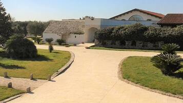 A paved pathway leading to a building with a tiled roof and a stone wall.