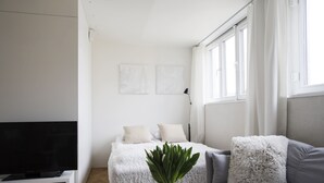 Una habitación moderna y bien iluminada con una cama, un sofá, un televisor y obras de arte en las paredes.