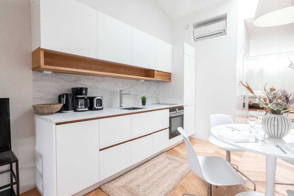 A modern kitchen with white cabinets, a wooden countertop, and a built-in oven.