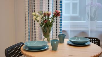 Una mesa de madera redonda con dos platos azules y una taza del mismo color, junto con un jarrón de flores.