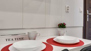 A kitchen counter with a tea time sign, white cabinets, and a small potted plant.