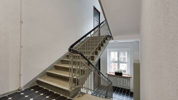 A staircase with a metal railing, a tiled floor, and a window with a plant on the landing.