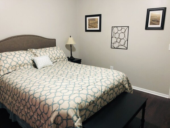 A neatly made bed with patterned bedding, a bedside lamp, and two framed pictures on the wall.