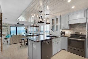 Enjoy ocean views from the kitchen window, featuring a central island with a dishwasher, stainless steel range, and double sink.