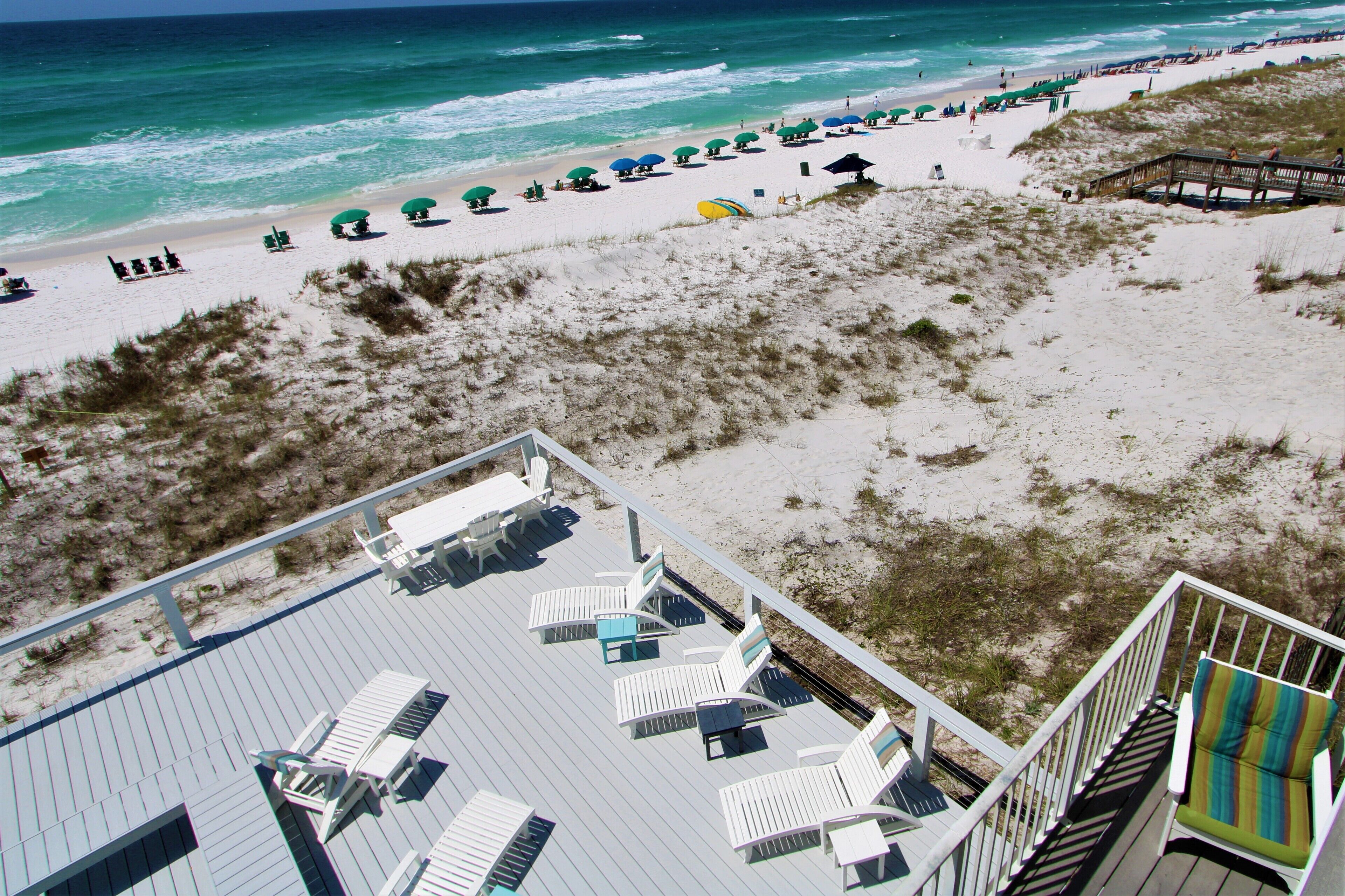 A beach with white sand, green umbrellas, and lounge chairs.