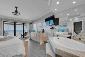 Relax in this serene bedroom with a large bed, sitting area, and ocean views through a sliding glass door.