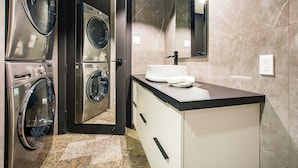 A modern bathroom with a built-in washer and dryer, a sink, and a large mirror. - Les Lofts de la Gare - By Les Lofts Vieux-Quebec (Québec City)