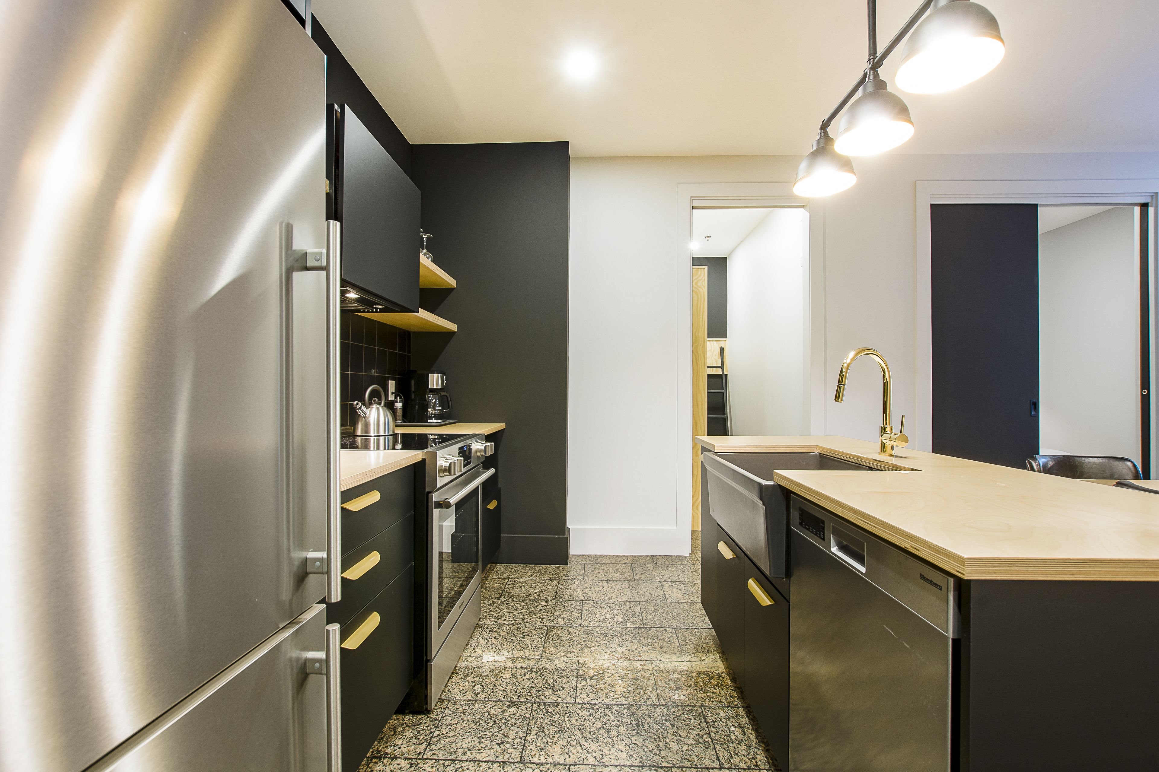 Una cocina moderna con electrodomésticos de acero inoxidable, encimera de madera y salpicadero negro.