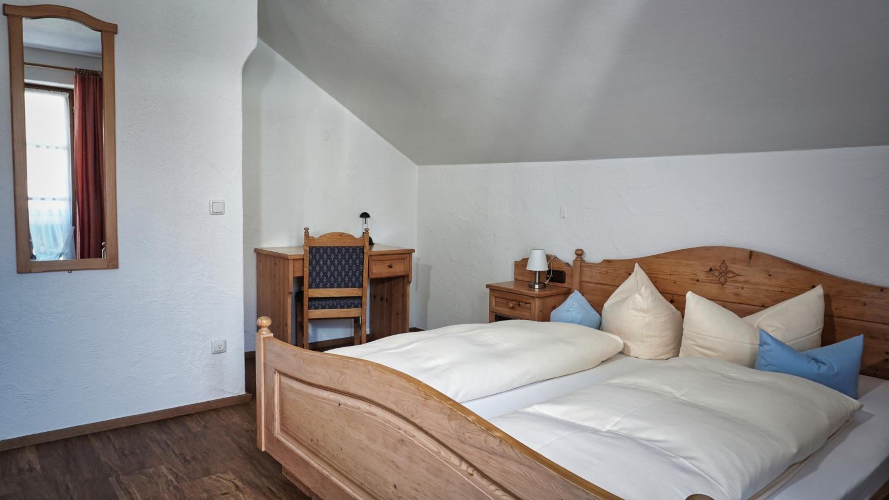 Un dormitorio con una cama de madera, una mesita de noche, un aparador y un espejo.