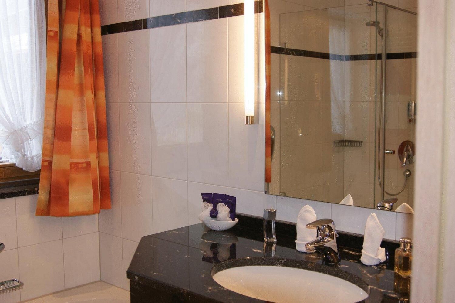 Ein Badezimmer mit Glasdusche, Waschbecken und Spiegel.