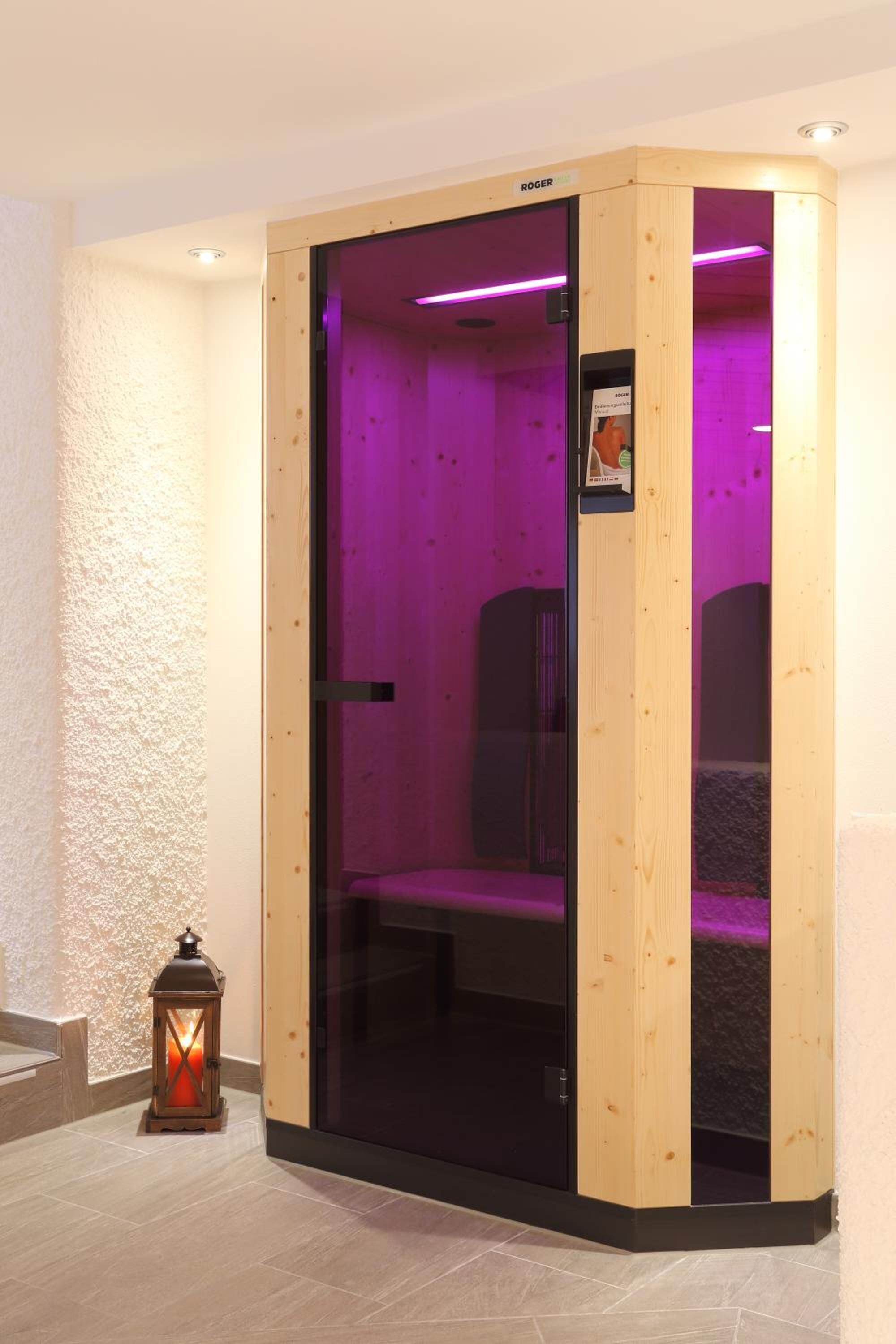 A sauna room with a wooden exterior, glass door, and purple lighting.