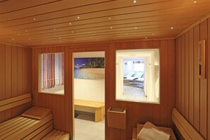 A sauna room with wooden benches, a bench with a towel, and a window with a view of a pool and lounge chairs. - Hotel Feldmeier (Oberammergau)