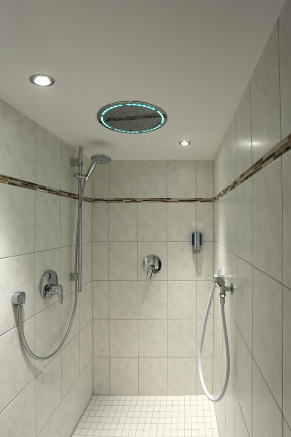 A modern shower with a handheld showerhead and a fixed wall-mounted showerhead. - Hotel Feldmeier (Oberammergau)