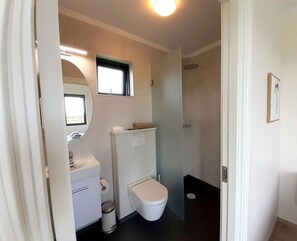 A compact bathroom with a toilet, sink, and shower.