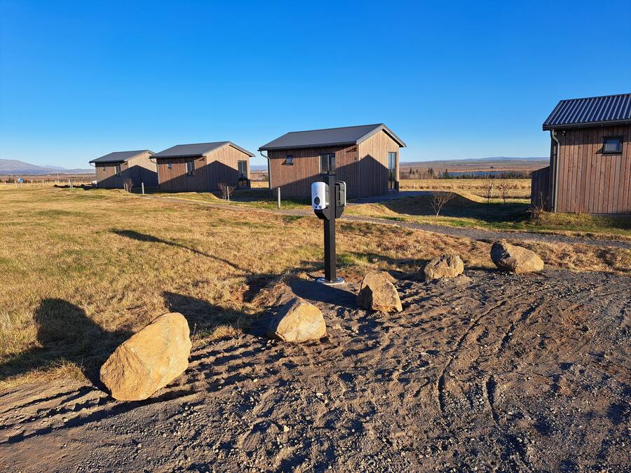 Un paisaje rural con cabañas de madera, un camino de grava y grandes rocas.