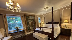A four-poster bed with a canopy, a sitting bench, a chandelier, and a large window with curtains. - Park Place Inn and Cottages (Sanford)