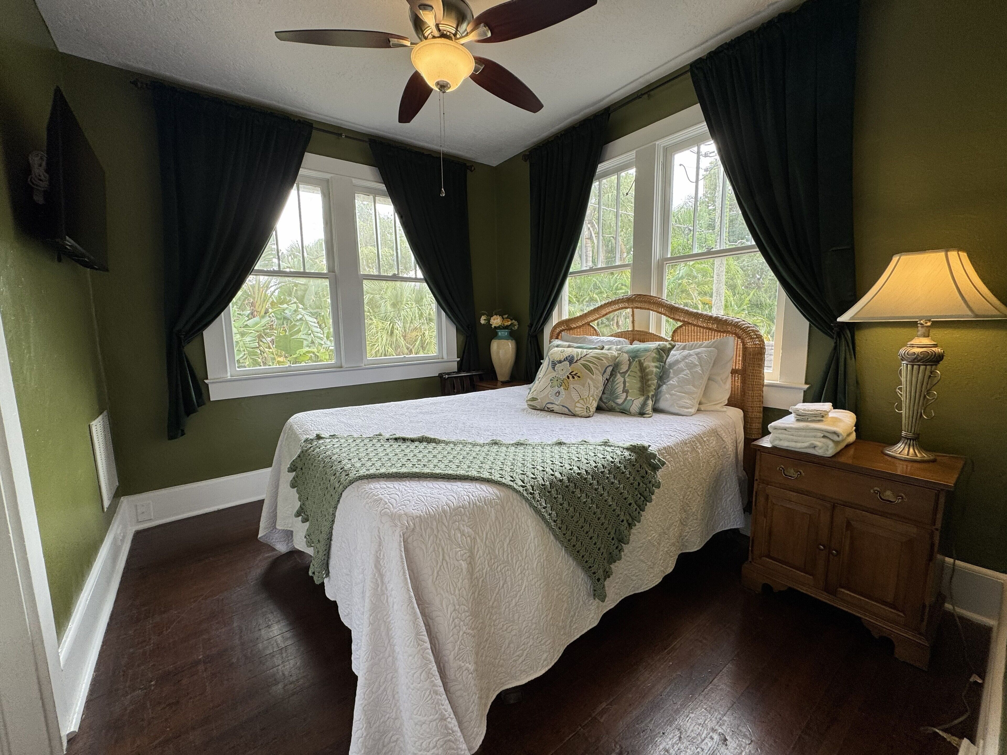 A bedroom with a bed, a nightstand, a lamp, and a ceiling fan.