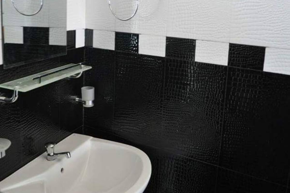 A bathroom with a white sink, black and white tiled walls, and a towel rack.