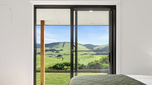 Une pièce dotée d’une grande porte-fenêtre coulissante donnant sur un balcon avec vue sur la campagne.