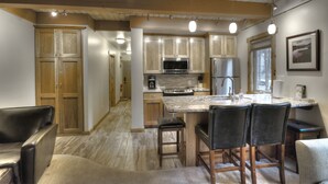 Eine moderne Küche mit Holzschränken, einer zentralen Kochinsel mit Barhocker und Pendelleuchten.