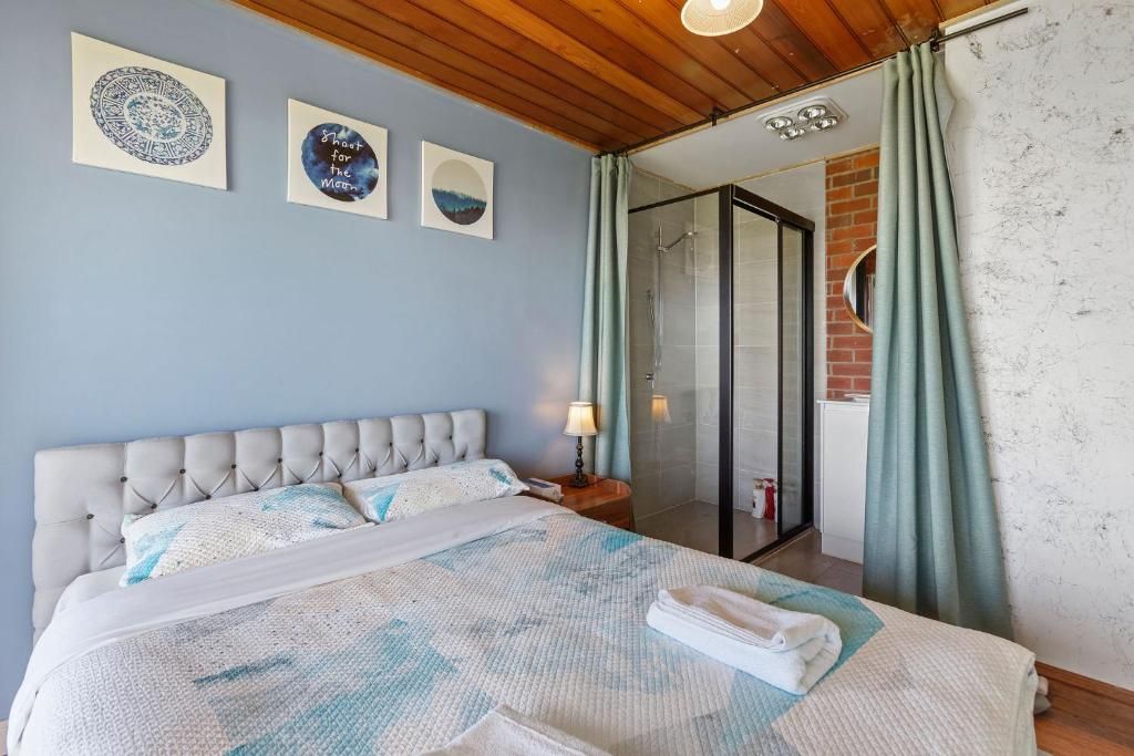 A bedroom with a bed, a nightstand, a lamp, and a view of a shower area.