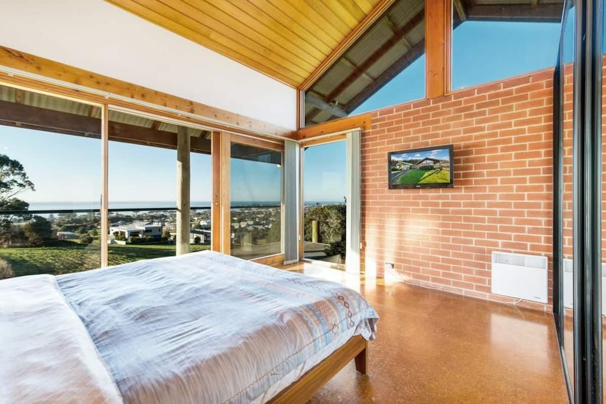 A bedroom with a large bed, a brick wall, and a view of the landscape.
