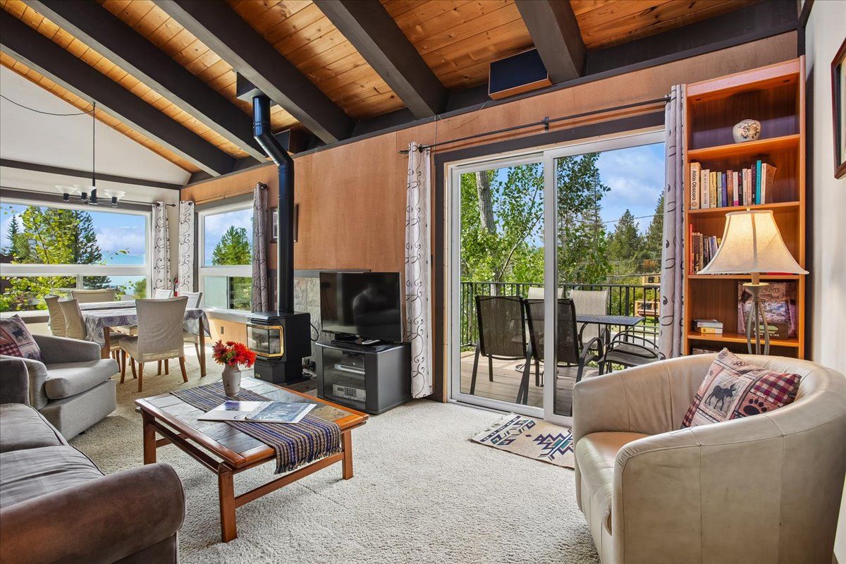 A modern living room with a fireplace, comfortable seating, and a view through glass doors.
