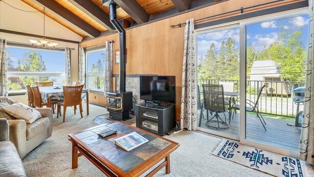Ein gemütliches Wohnzimmer mit Kamin, Fernseher, Essbereich und großen Schiebegläsern zur Terrasse.