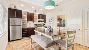 A modern kitchen with dark wooden cabinets, stainless steel appliances, and a white dining table with benches. - 2BR Beach Style w Pool Beach Club Siesta 204C RVA (Sarasota)