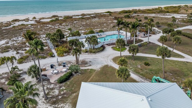 An aerial view of a resort with a swimming pool, palm trees, and a beach. - Fantastic Gulf View Villa with Resort Amenity Access! B3312A (Englewood)
