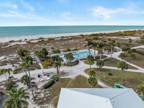 Ein Luftbild eines Resorts mit Schwimmbad, Palmen und Strand.
