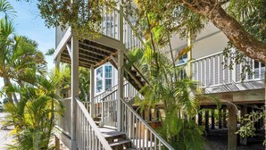 A wooden staircase leading to a building with multiple windows, surrounded by palm trees and a covered outdoor area. - Fantastic Gulf View Villa with Resort Amenity Access! B3312A (Englewood)