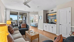 A spacious living area with a ceiling fan, a sofa set, a coffee table, and a television mounted on the wall. - Fantastic Gulf View Villa with Resort Amenity Access! B3312A (Englewood)