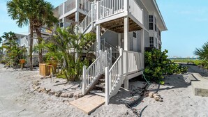Ein mehrstöckiges Strandhaus mit Balkon und einer Treppe, die zu den oberen Stockwerken führt.