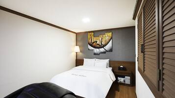 Una habitación de hotel con una cama, una mesita de noche, una lámpara y una obra de arte en la pared.