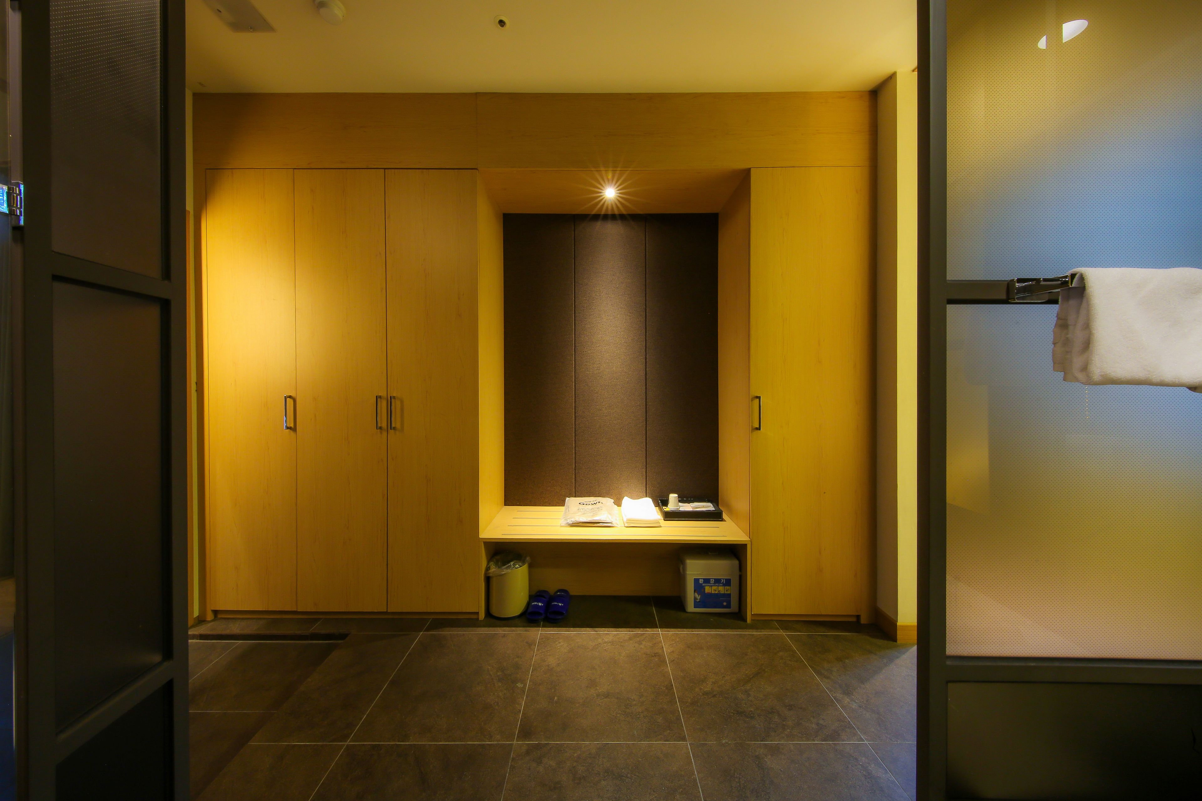 A modern bathroom with a wooden vanity, a towel rack, and a trash bin.