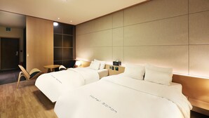 A hotel room with two beds, a small table, and a chair. - Bolton Hotel (Gwangju)