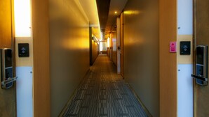 A hotel hallway with carpeted floors, wooden walls, and doors with electronic keycard readers. - Bolton Hotel (Gwangju)