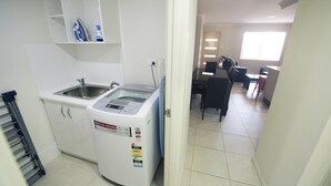 Une petite cuisine équipée d’un lave-linge, d’un évier et d’un étendoir.