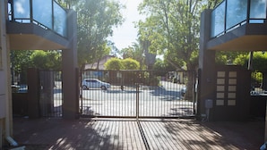 A gated entrance to a building with a brick pathway leading to a parking area. - Midland Haven - Midland WA (Midland)