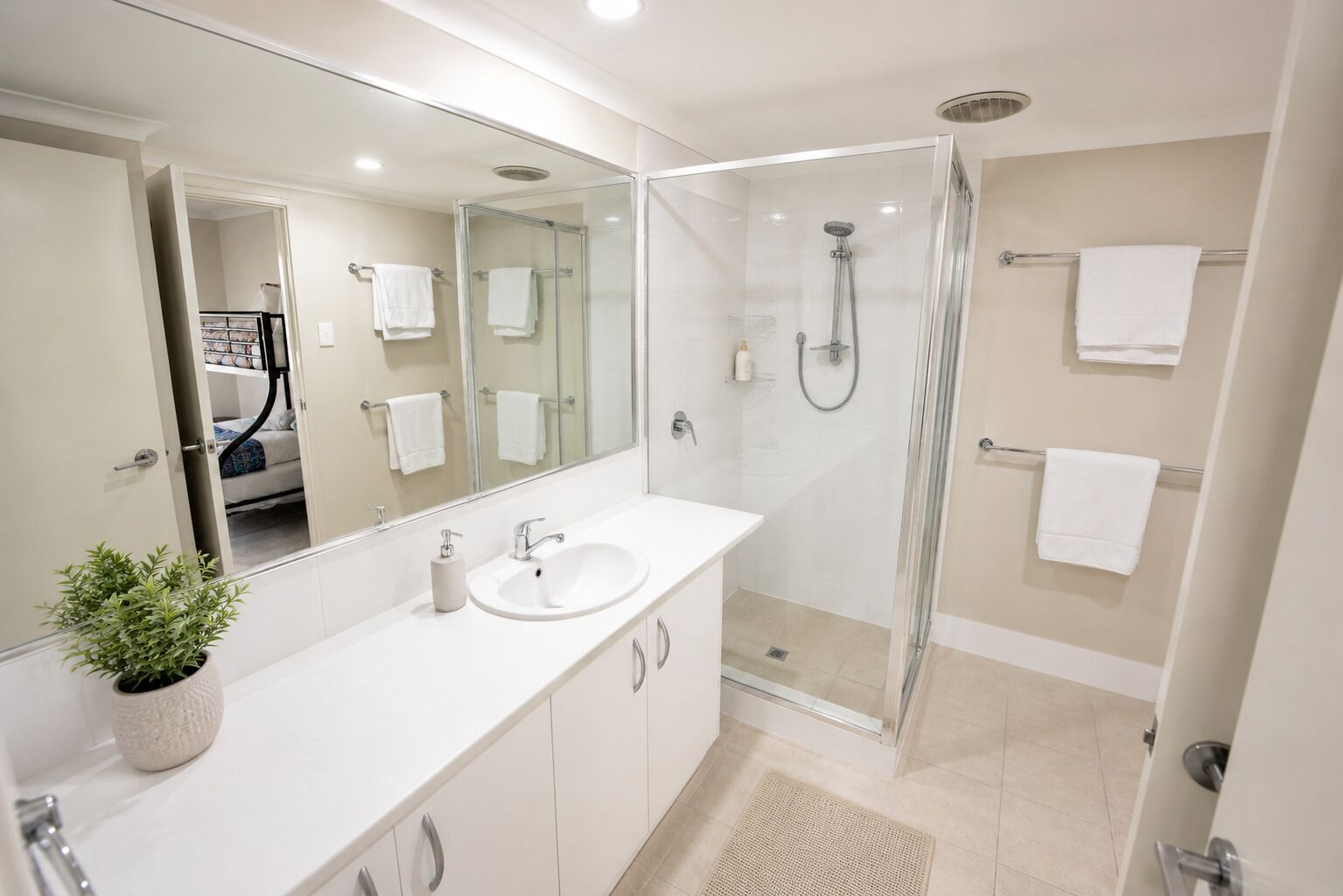 A modern bathroom with a glass-enclosed shower, a white sink, and a large mirror.