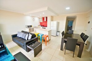 Um apartamento moderno com sala de estar, área de refeições, cozinha compacta e um banheiro pequeno.
