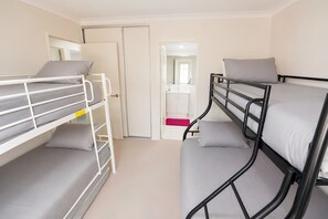 A room with bunk beds, a bathroom with a mirror, and a door leading to another room. - Midland Haven - Midland WA (Midland)