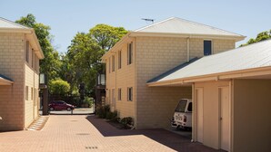 A residential area with brick buildings, a paved walkway, and a parked white van. - Midland Haven - Midland WA (Midland)