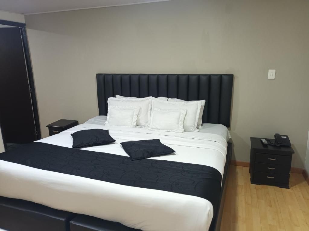 Una habitación de hotel con una cama, una mesita de noche y un aparador.